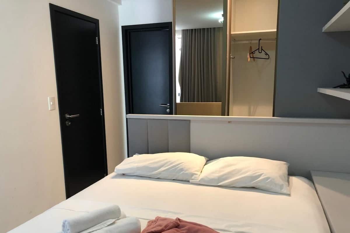 Een hotelkamer met een bed, een deur, een spiegel en een kapstok.
