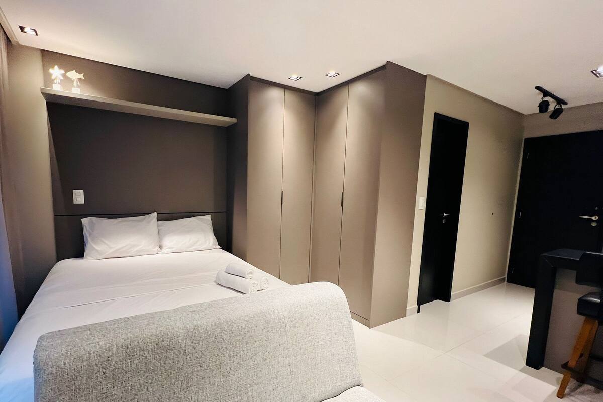 Een moderne slaapkamer met een groot bed, een kledingkast en een bureau.