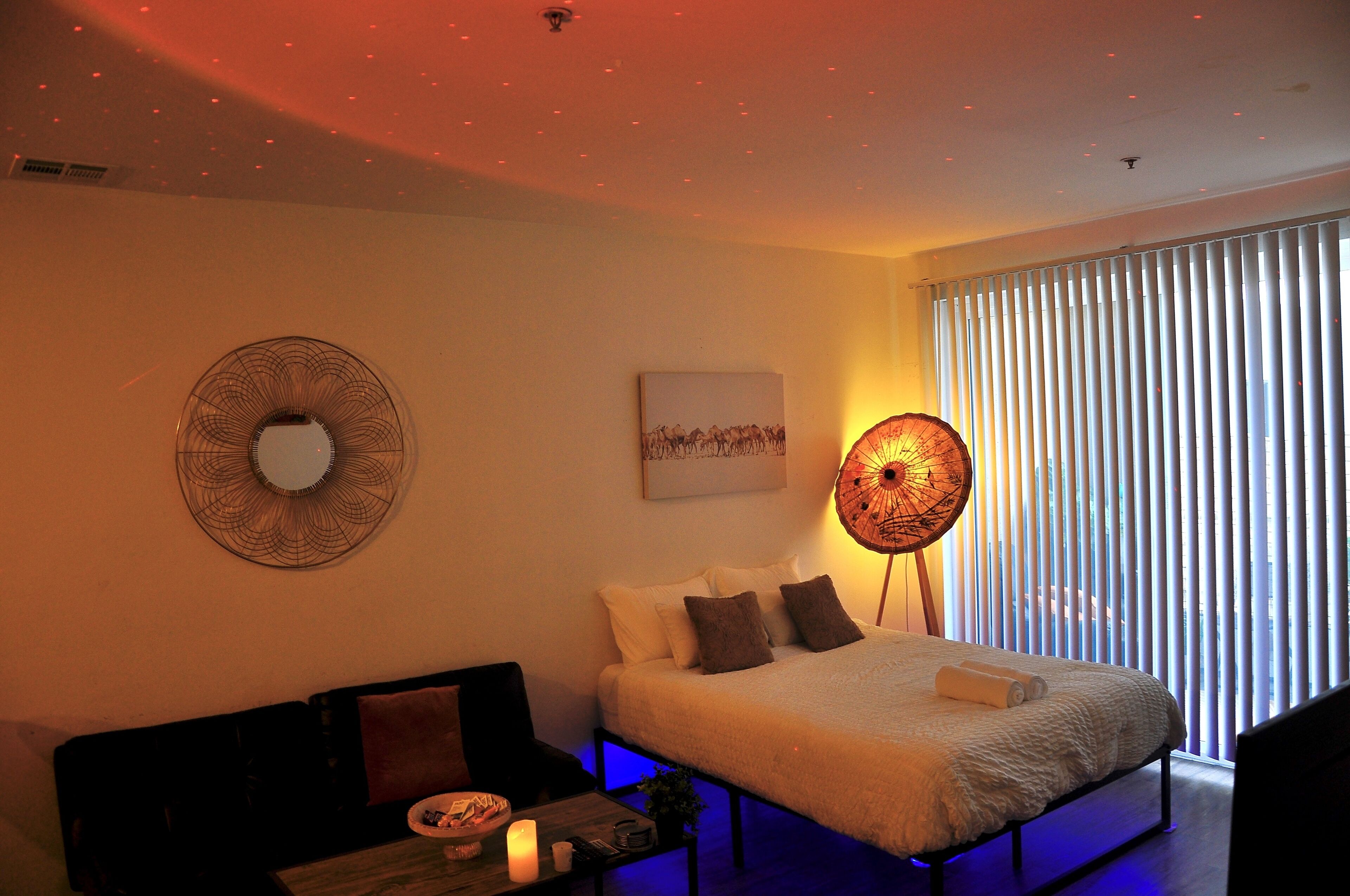 A bedroom with a bed, bedside table, and a wall-mounted lamp.