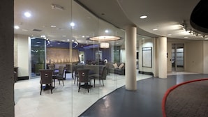 Un vestíbulo moderno con paredes de vidrio, zonas de estar e iluminación central.