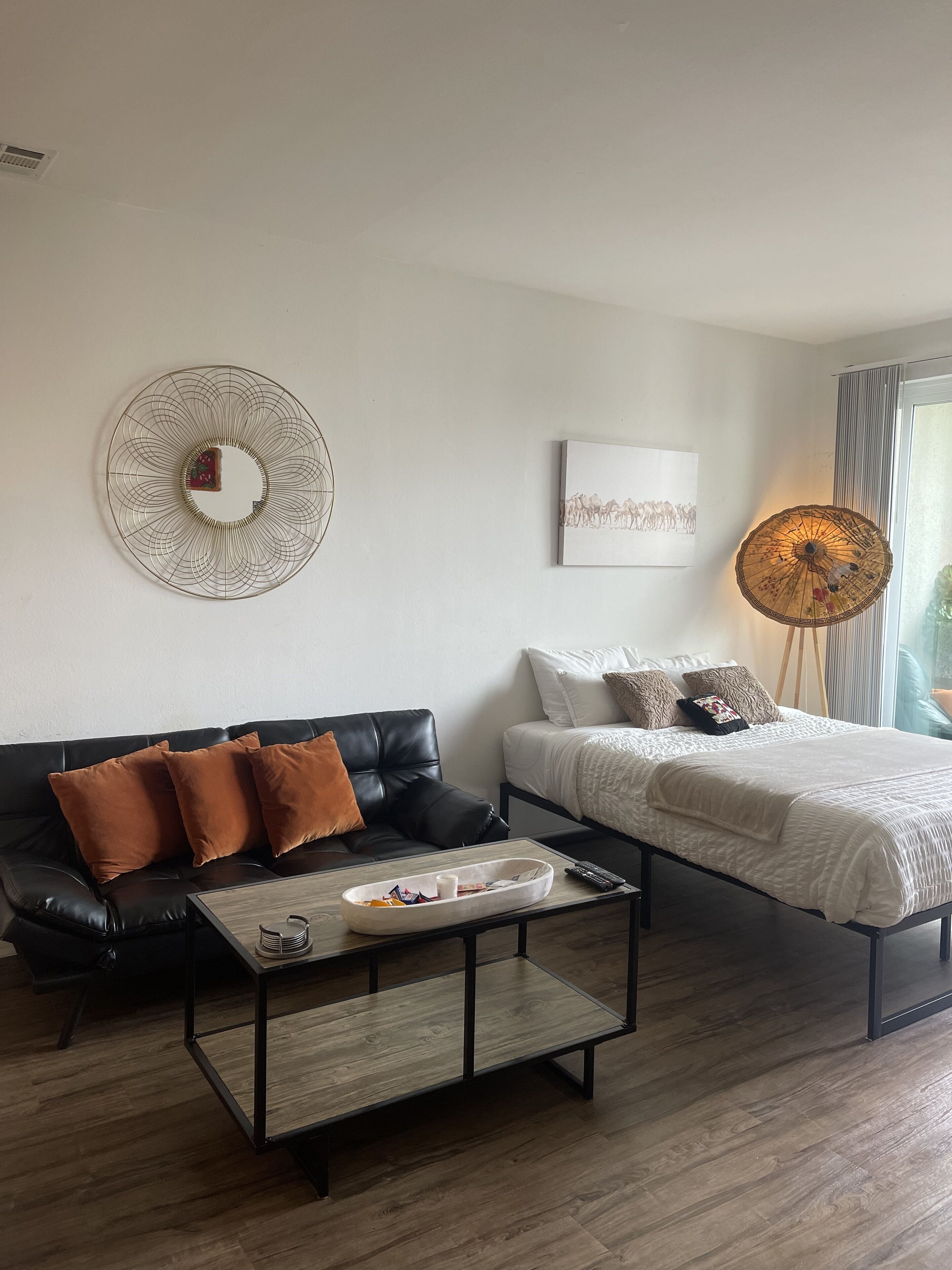 Een moderne woonkamer met een zwarte leren bank, een wit bed en een salontafel.