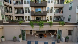 Un edificio residencial de varios pisos con balcones, mobiliario exterior y macetas con plantas.