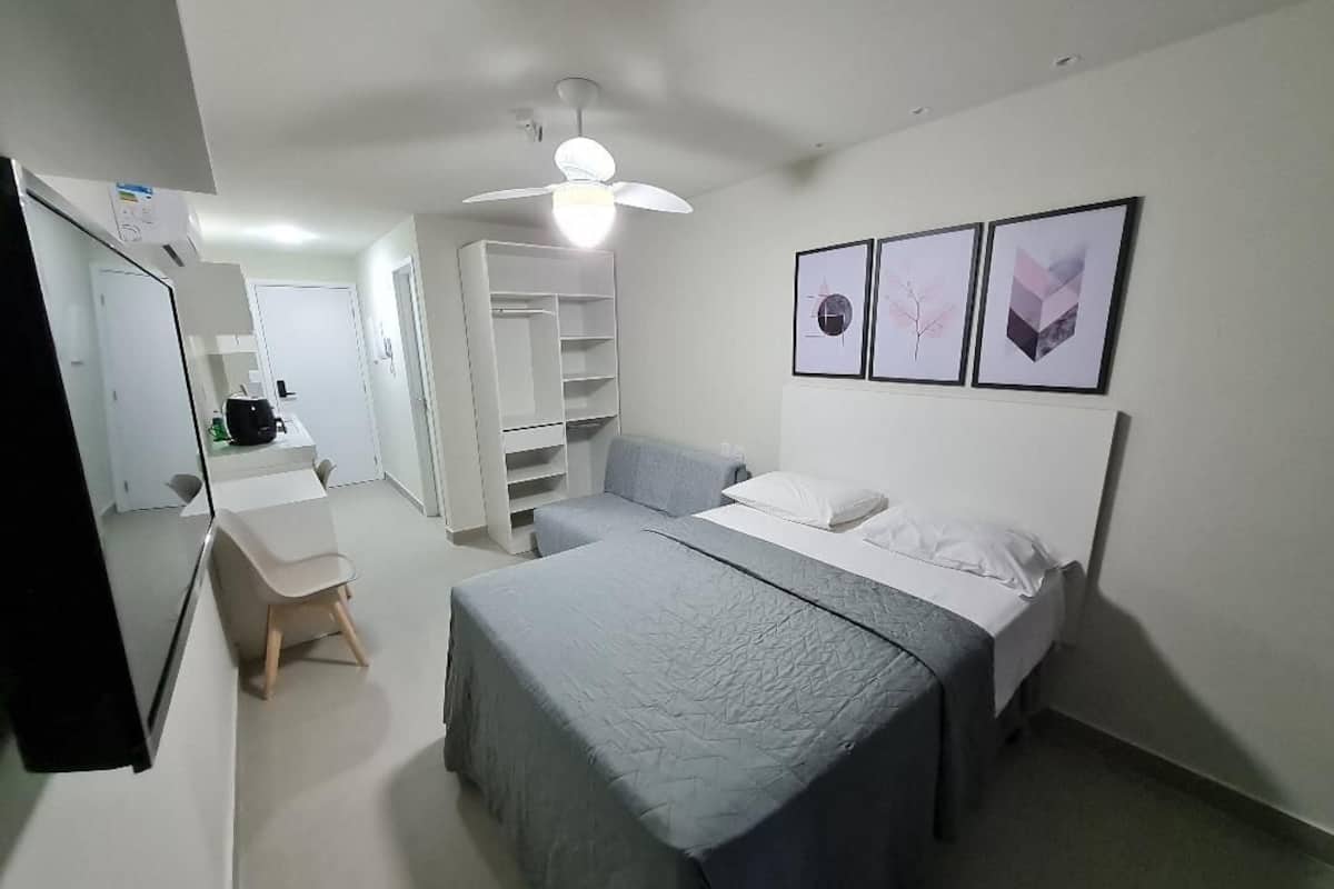 A bedroom with two beds, a desk, a chair, a wardrobe, and a ceiling fan.
