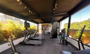 Un gimnasio con cintas de correr, máquinas de pesas y vistas a zonas verdes.