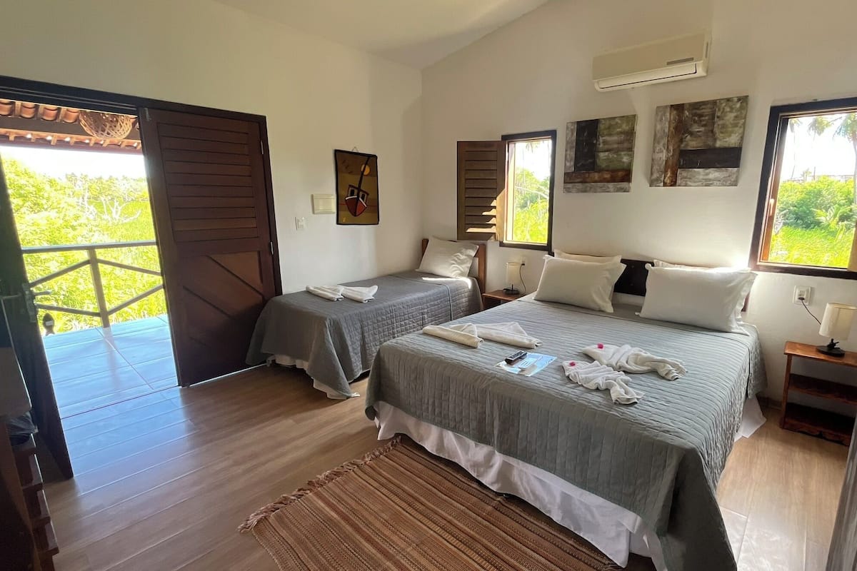 Ein Schlafzimmer mit zwei Betten, Holzboden, einem Balkon und Kunstwerken an den Wänden.