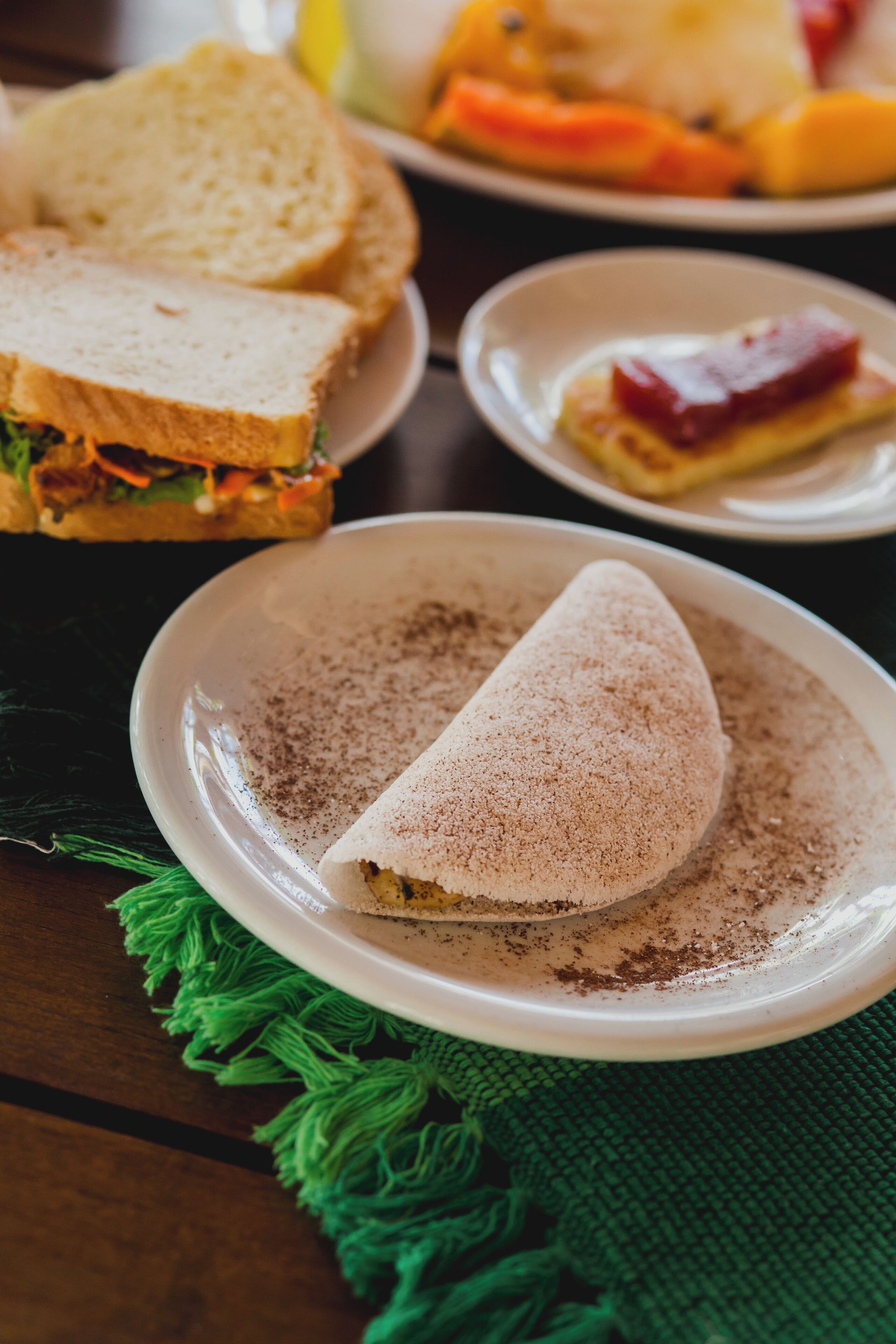 A sandwich on a plate with a green cloth underneath.