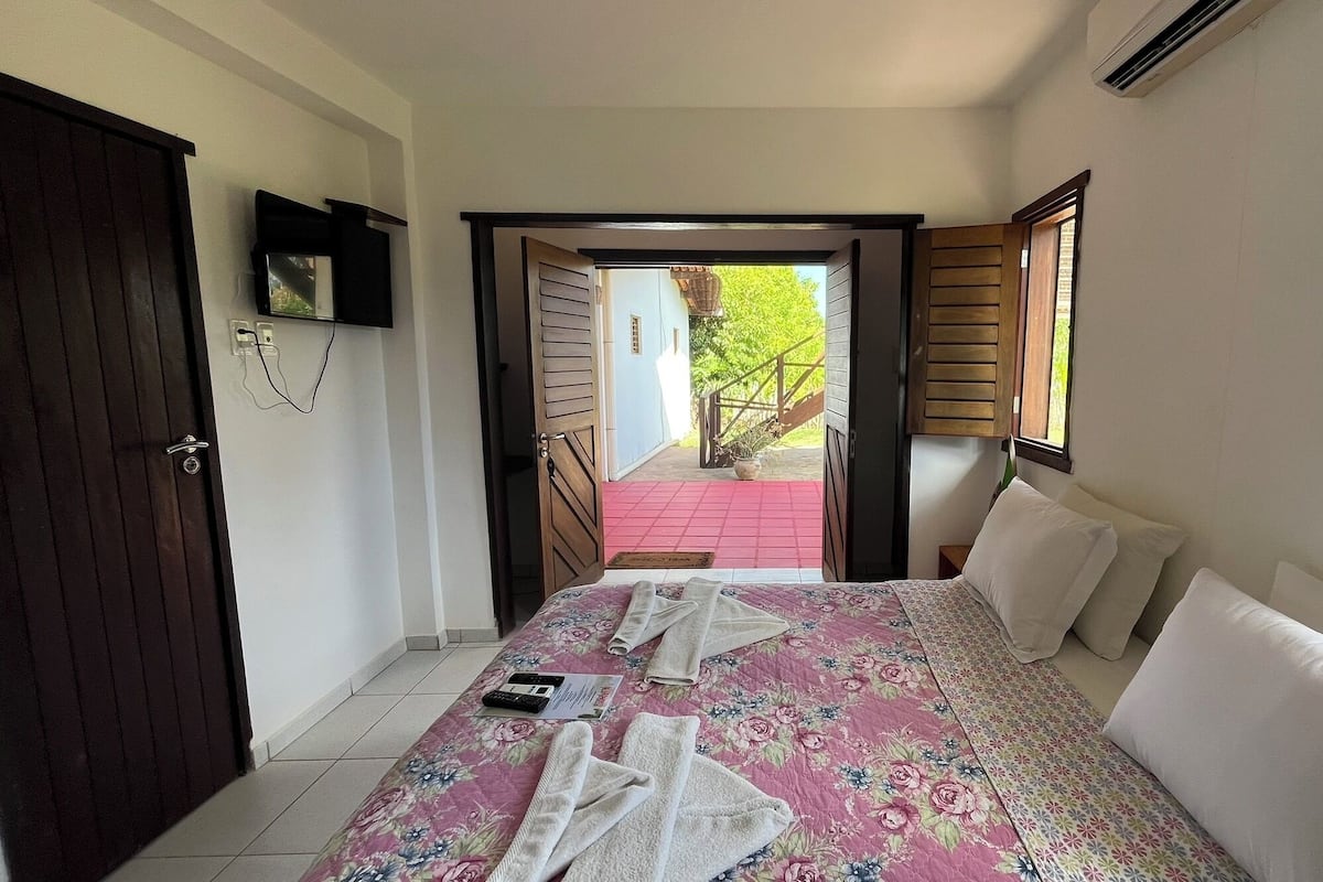 Ein Hotelzimmer mit Bett, Schreibtisch, Stuhl, Fenster und Tür.