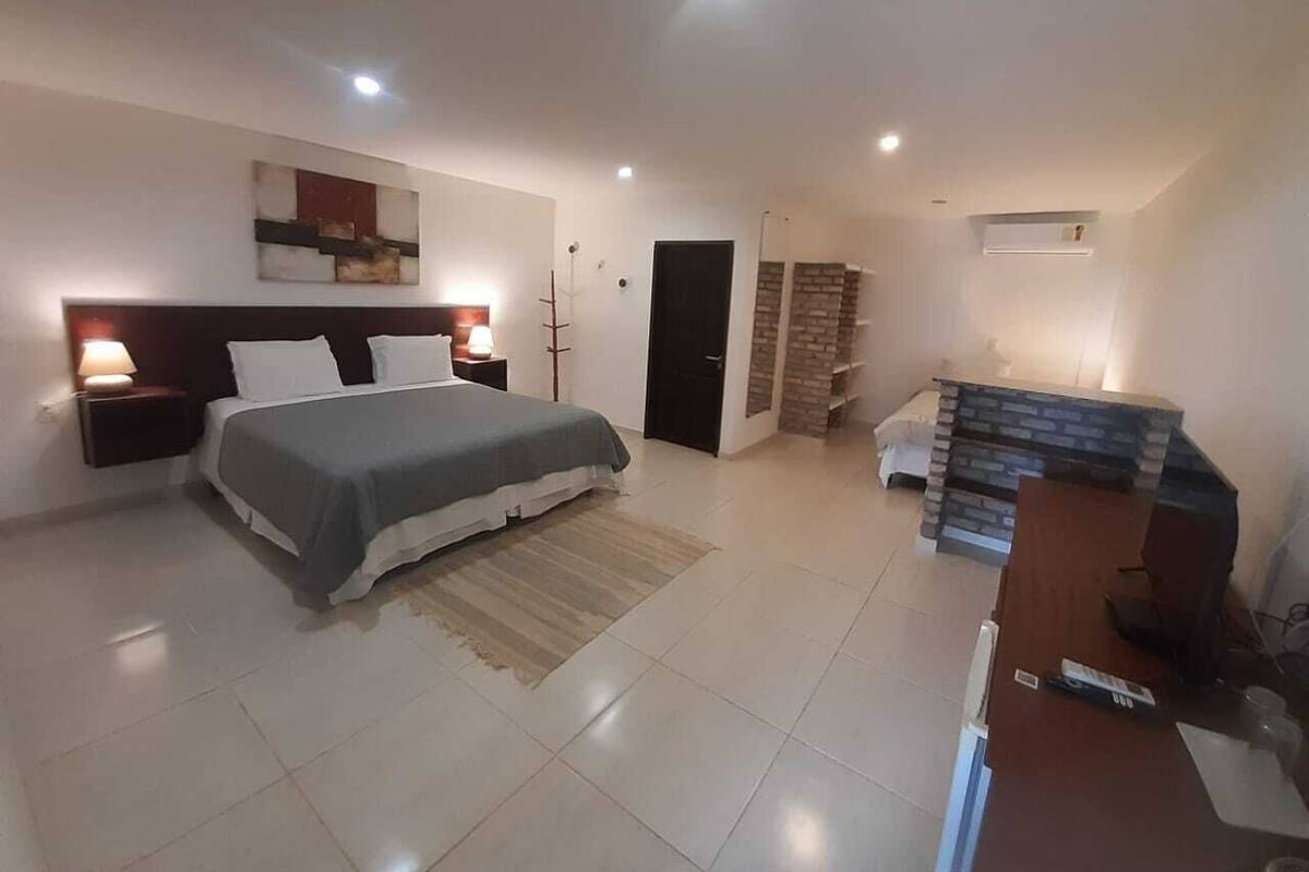Ein Schlafzimmer mit Bett, Nachttischen, einem Schreibtisch und einer Treppe.