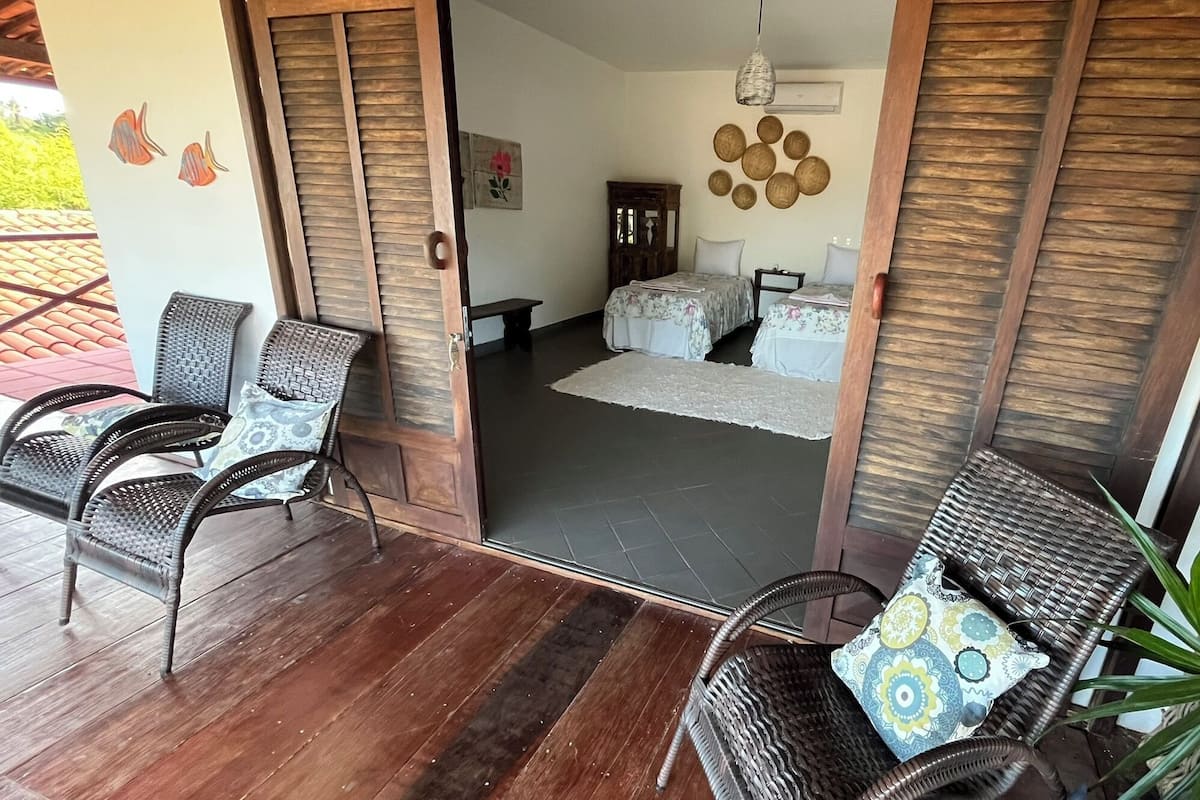Ein Zimmer mit einem Bett, zwei Stühlen, einem kleinen Tisch und einer Wandverzierung.