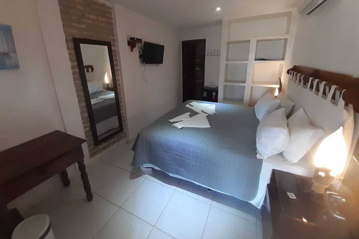 Ein Schlafzimmer mit Bett, Nachttisch, Spiegel, Fernseher und Kleiderschrank.