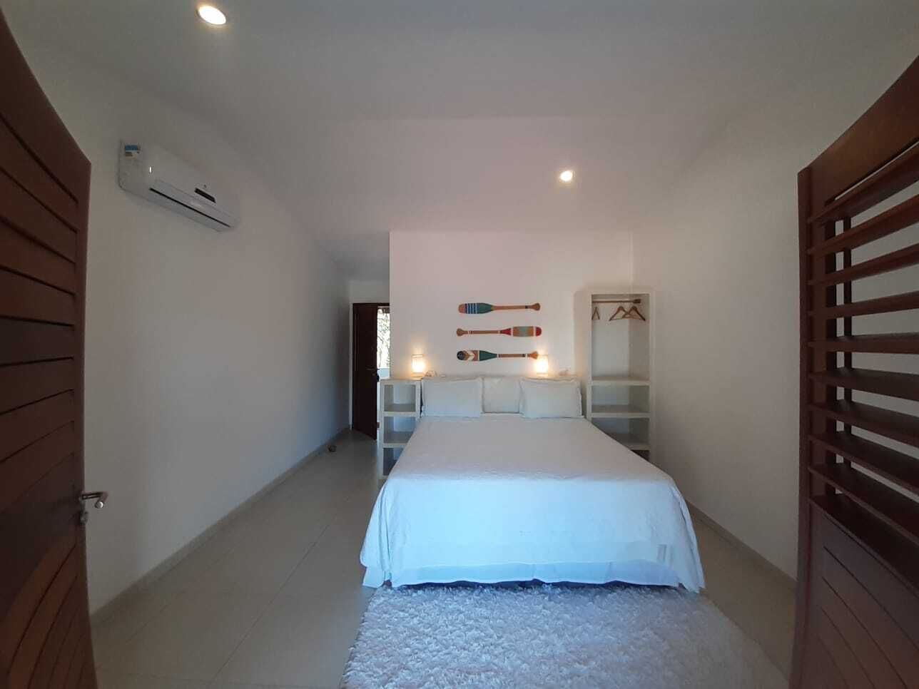 Ein Schlafzimmer mit einem Bett, einer weißen Wand mit Ablagefläche und einer Klimaanlage.