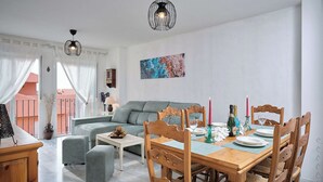 Un salon moderne avec un canapé gris, une table à manger en bois et des chaises. Un tableau est accroché au mur et il y a une fenêtre avec des rideaux.