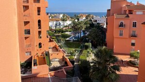 Un quartier résidentiel avec des bâtiments aux façades orange, une piscine et une vue sur la mer.
