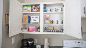 Eine Küche mit einer Kaffeebar, die Kaffeekapseln, eine Kaffeemaschine und verschiedene Kaffeezubehörteile beherbergt.