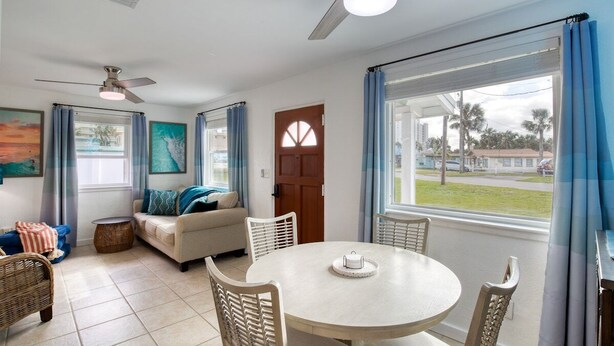 A living room with a round table, white chairs, a sofa, and a ceiling fan. - 60 Seconds to Sand (Ormond Beach)