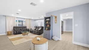 A modern living room with a leather sofa, a glass coffee table, and a grey cabinet. - Sunset Lanai & Screened Pool · Waterfront Views (Cape Coral)