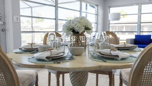A round dining table with a vase of white flowers, clear glassware, and neatly arranged plates and cutlery. - Sunset Lanai & Screened Pool · Waterfront Views (Cape Coral)