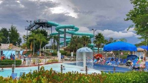 A water park with a large water slide, a pool, and lounge areas. - Sunset Lanai & Screened Pool · Waterfront Views (Cape Coral)