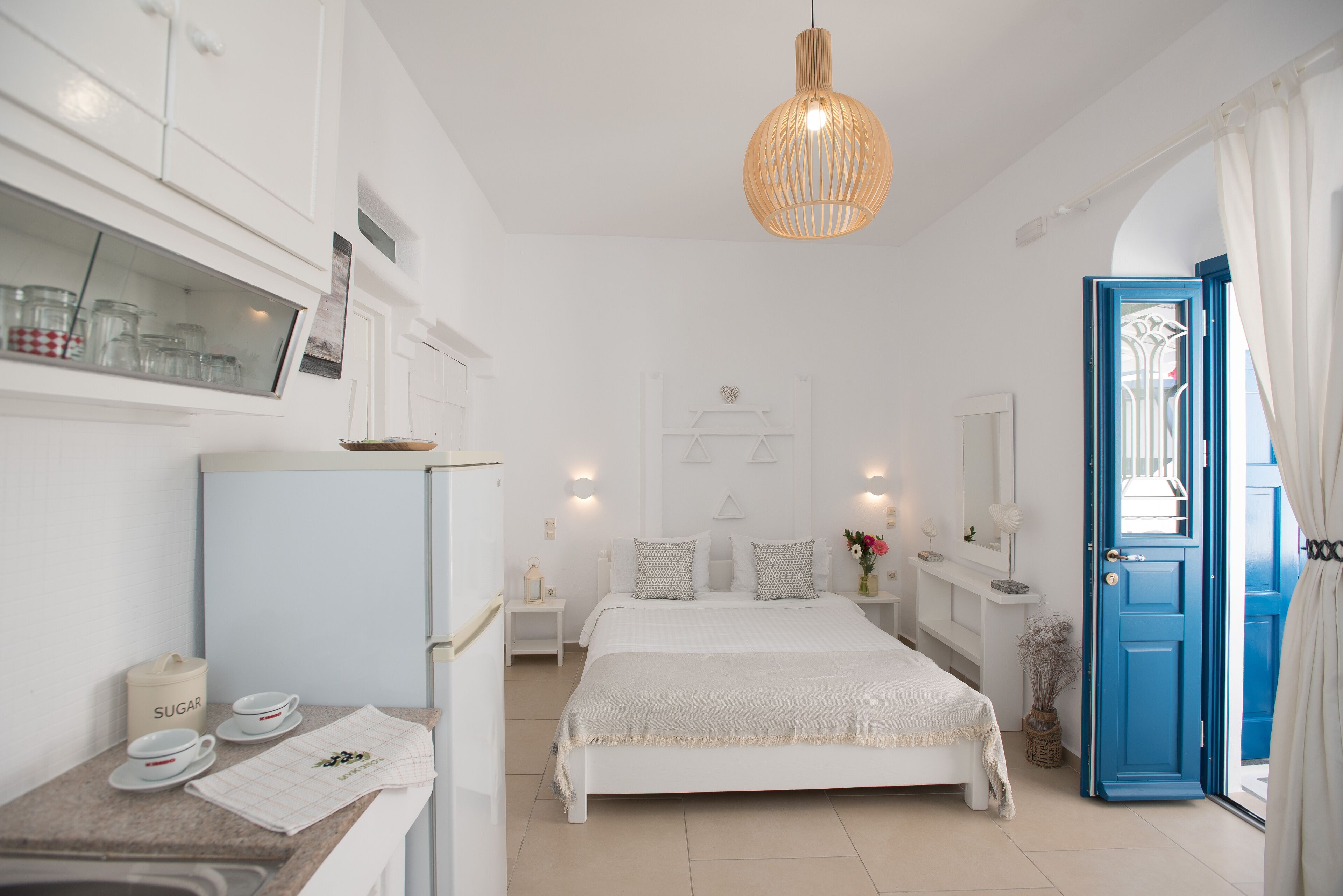 A bedroom with a bed, a nightstand, a dresser, a mirror, a window with curtains, and a door.