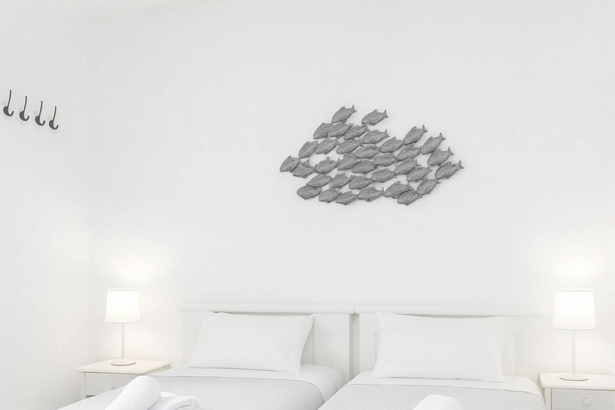 Una habitación de hotel con dos camas individuales, ropa de cama blanca, una obra de arte colgada en la pared y lámparas de noche.