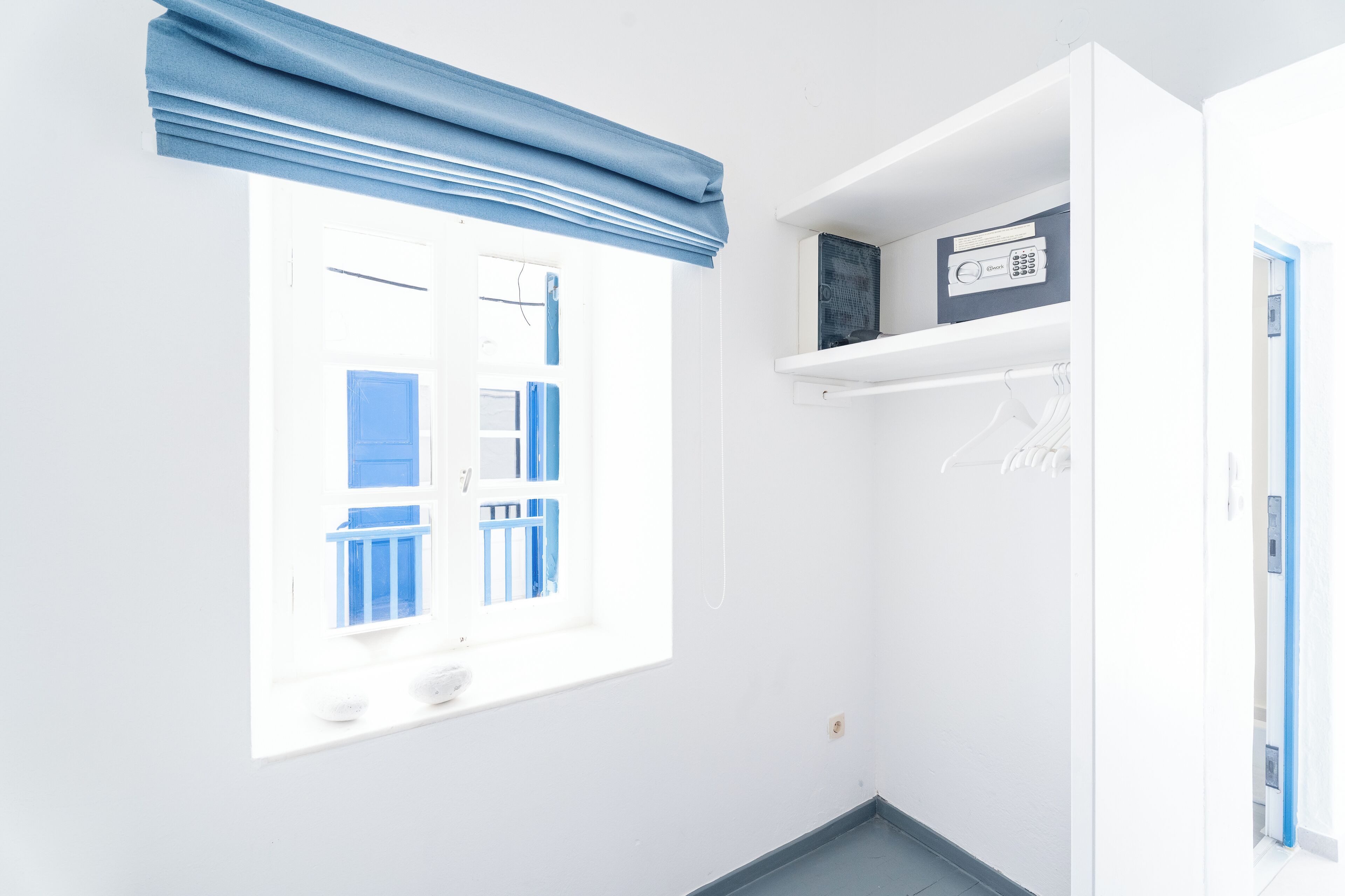 Una habitación luminosa con una ventana, un estante con un dispositivo y una puerta.