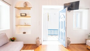 A modern living room with a sofa, wooden shelves, and a TV mounted on the wall. - Eleanna's Mykonos (Mykonos)