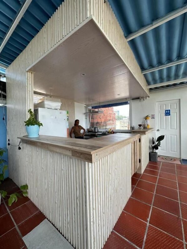 Cozinha com bancada de madeira e teto de metal corrugado.