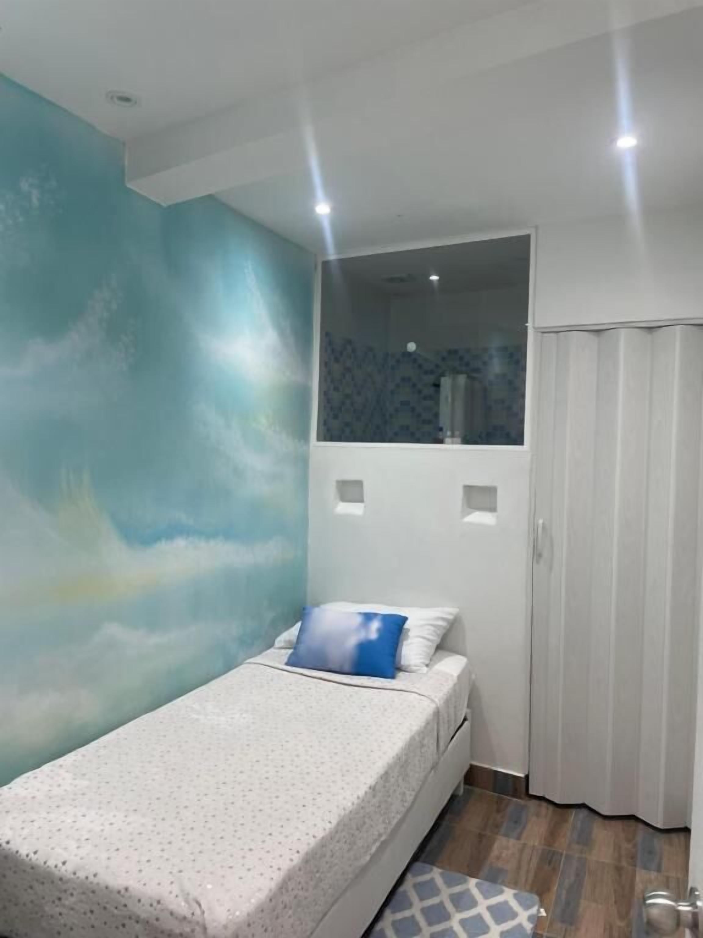 A bedroom with a bed, a wall mural, a window, and a door.