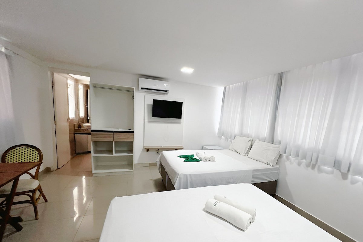 A hotel room with a bed, a desk, a chair, a TV, and a bathroom.