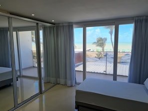 A hotel room with a balcony, a bed, and a view of the beach. - Miramar Na Praia (João Pessoa)
