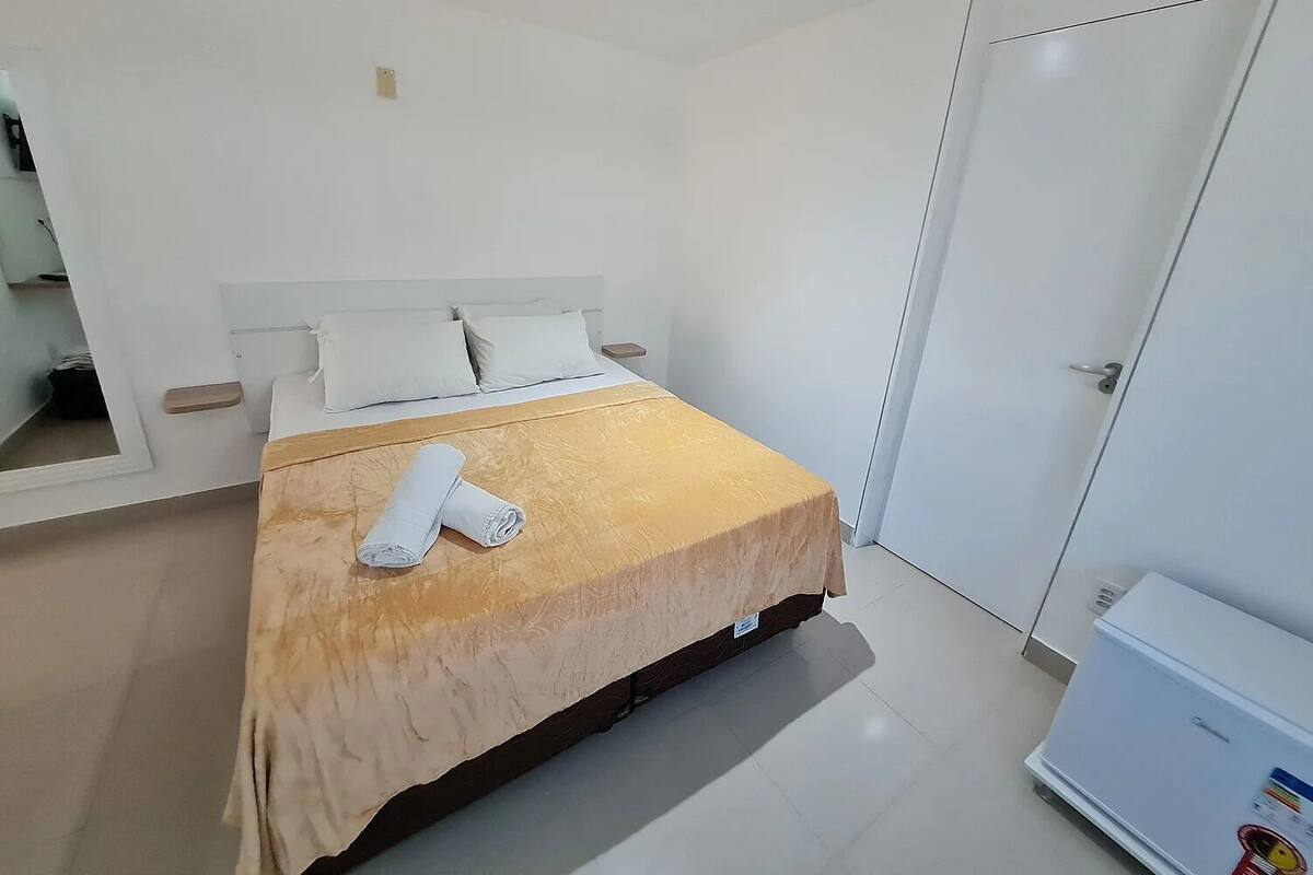 A hotel room with a bed, a wardrobe, and a small table.