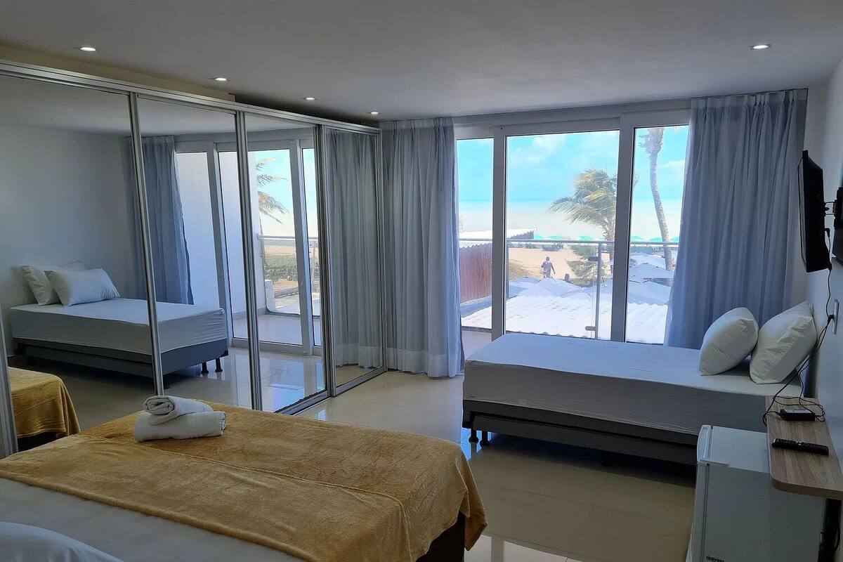 A hotel room with a bed, a seating area with a view, and a small kitchenette.