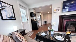 A modern living room with a sofa, a dining table set for two, and a kitchen in the background. - Adorable 1 BR on the mount (Pittsburgh)