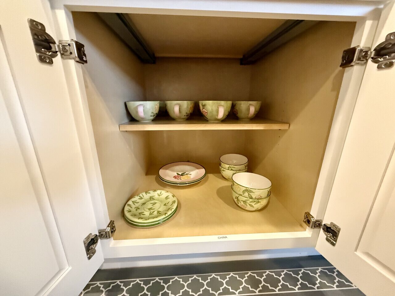 A cabinet with shelves holding various ceramic dishes and bowls.