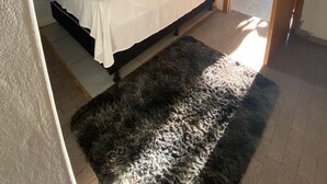 A bedroom with a bed, a ceiling fan, a window with curtains, and a door leading to another room.