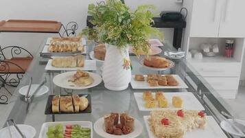 Mesa de jantar com diversos alimentos e um arranjo de planta decorativa.