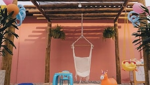 A cozy outdoor seating area with a hammock, a small blue stool, and a toy horse.