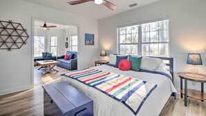 A bedroom with a large bed, a ceiling fan, a window with a view, a bedside table, and a nightstand. - Waterfront, 7 acres; Stunning Home on Coastal Tidal Marsh w/Private Dock (Shellman Bluff)