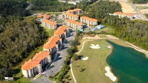 Vista aérea de un resort con varias edificaciones, un campo de golf y una masa de agua.