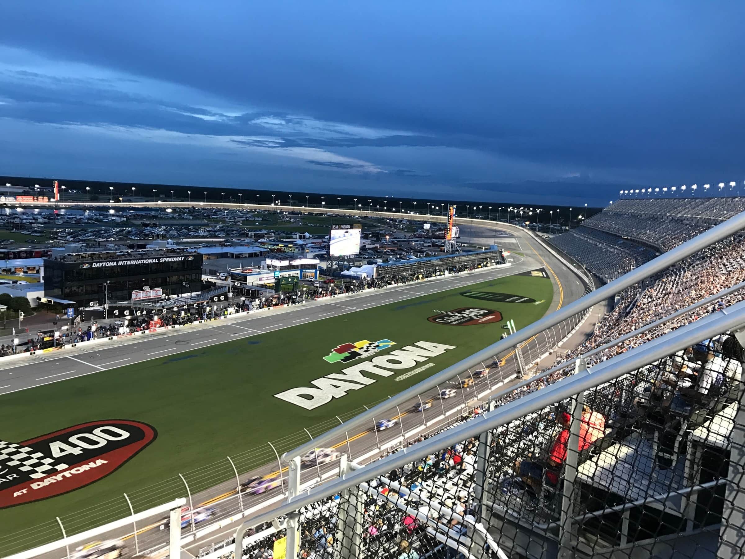 A view of a large stadium with a racing track, seating areas, and a clear sky.