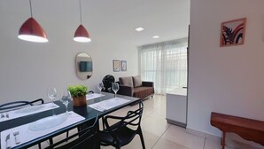 A modern dining area with a table set for two, a sofa, and a TV mounted on the wall. - Miramar Luxor Paulo Miranda - C. Branco (João Pessoa)