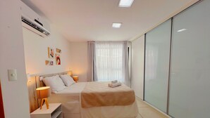 A modern bedroom with a bed, bedside tables, a lamp, artwork on the wall, and a sliding glass door closet. - Miramar Luxor Paulo Miranda - C. Branco (João Pessoa)
