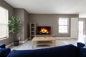 Relax in this stylish living room with a flat-screen TV, shelving, and comfortable sofas.