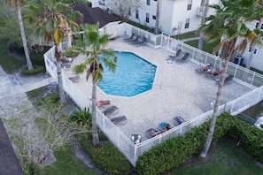 Relax by the pool surrounded by lush greenery and palm trees, with lounge chairs and umbrellas at your disposal.