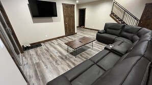 Una sala de estar moderna con un sofá seccional, una mesa de centro y un televisor de pantalla plana montado en la pared.
