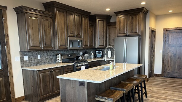 Una cocina con armarios de madera oscura, encimera de granito, refrigerador de acero inoxidable y una isla integrada con taburetes de bar.