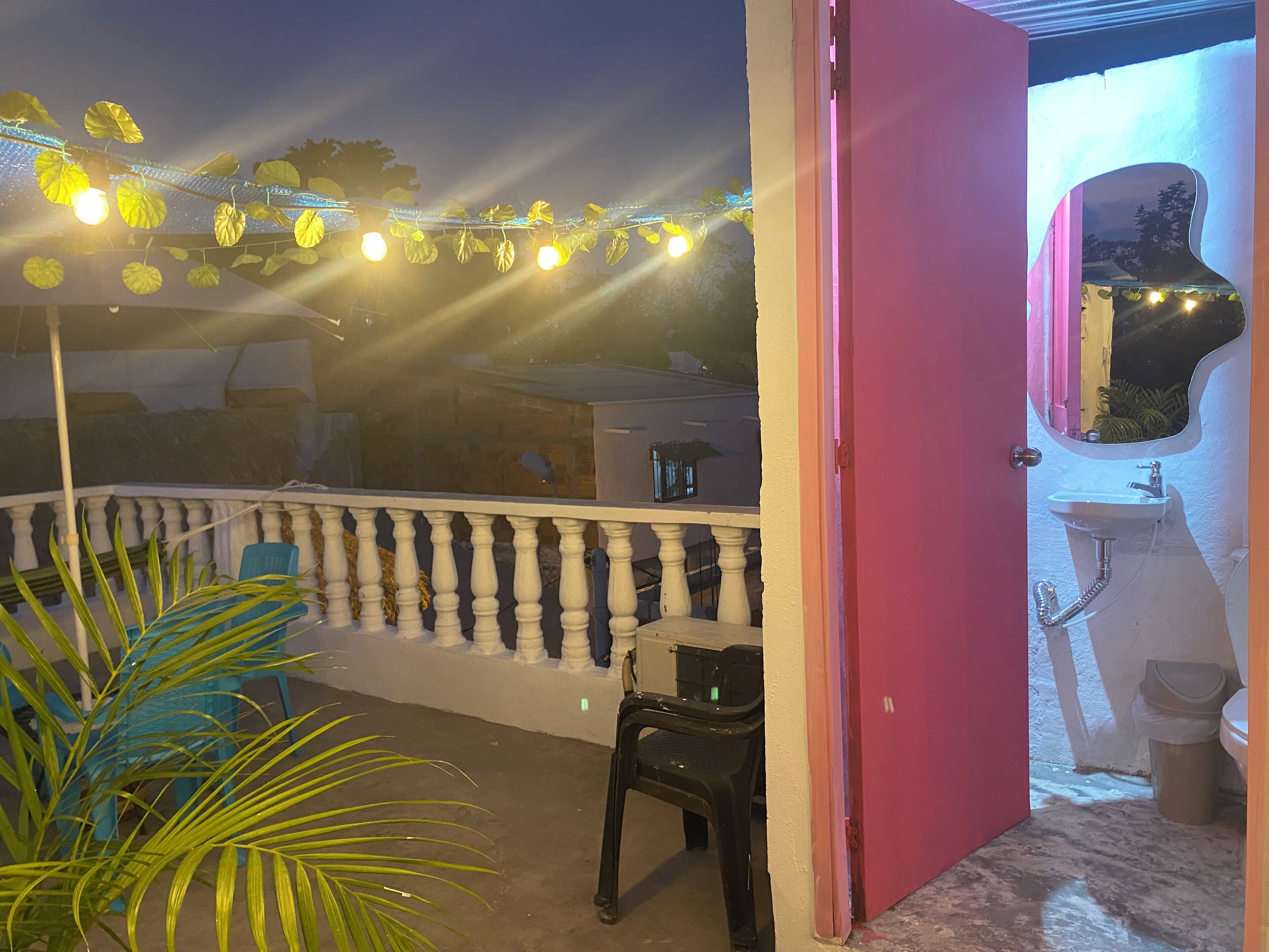A balcony with string lights, a chair, and a potted plant.
