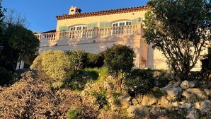 Un grand bâtiment doté d’un balcon, entouré d’arbres et de rochers.