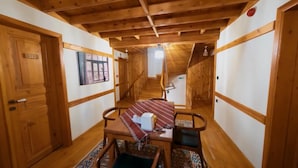 A wooden interior with a staircase, a dining table with a red and white tablecloth, and a patterned rug. - Utku Konağı (Bartin)