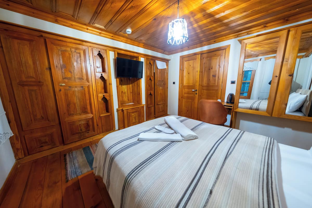 Un dormitorio con paneles de madera, una cama, un televisor y un espejo.